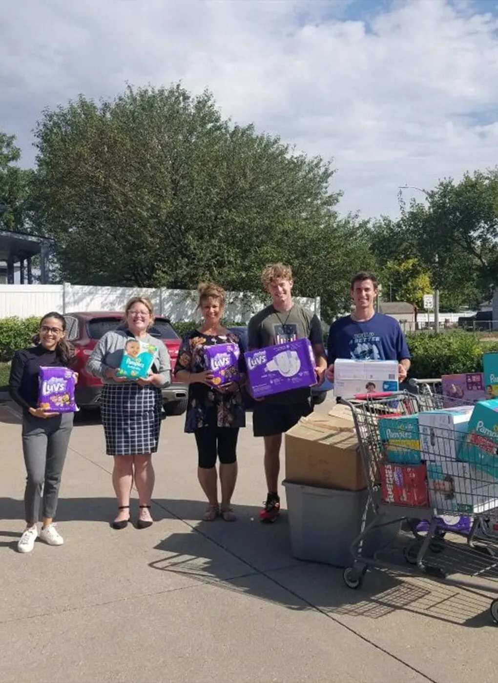 Five people standing outdoors with diaper packages